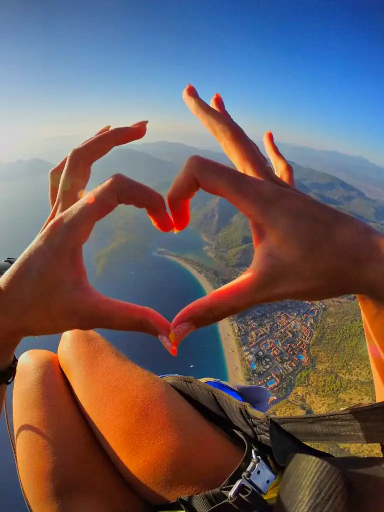A paragliding passenger creating a heart shape above the stunning blue lagoon, capturing the romance and beauty of Oludeniz