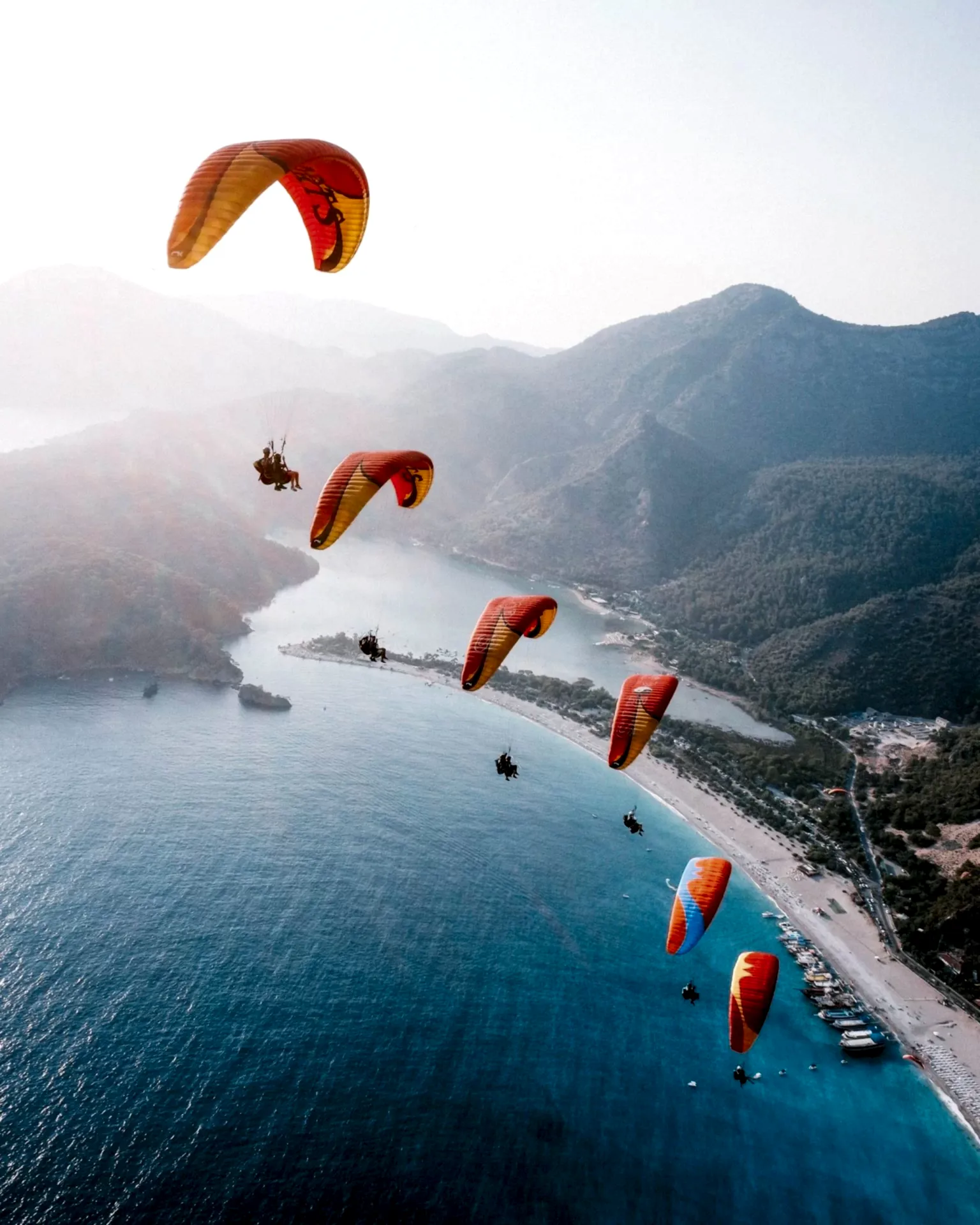 Six paragliders flying in perfect formation, side by side, showcasing precision and teamwork in the skies